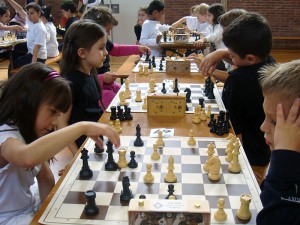 Kinder sitzen sich während der Mini-Schacholympiade beim Schachspiel gegenüber