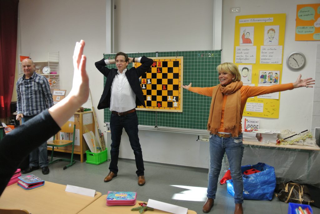 Schach-Yoga in der Praxis: Stiftungsrat Stefan Kindermann (Mitte) und Uschi Glas (re.) von brotZeit e.V. an der Grundschule in der Kleinfeldstraße in Germering