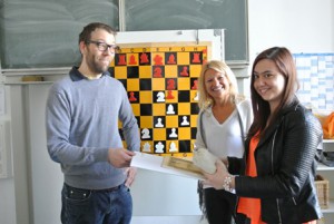 Schach-TeilnehmerInnen erhalten ein Schach-Set und Schachliteratur von Trainer Felix Brychcy (li.) und der Stiftungsvorsitzenden Dijana Dengler (Mitte)