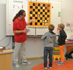 Schachlehrer Klaus de Francesco diskutiert mit Kindern eine Stellung am Demo-Brett